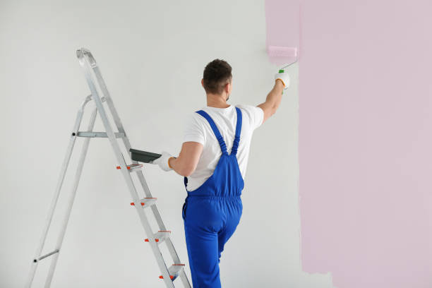 istock Man painting wall with light pink dye indoors, back view 1461683090