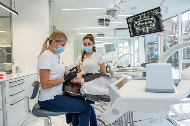 치과 의자에 앉아 있는 어린 소녀의 초상화는 여성 치과 의사와 조수에게 치료를 받고 있습니다. - dentist dental assistant dentist office dental drill 뉴스 사진 이미지