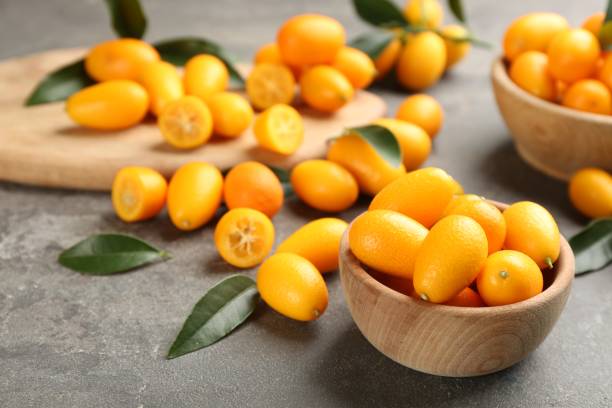 istock Fresh ripe kumquats in bowl on grey table, space for text 1461684928