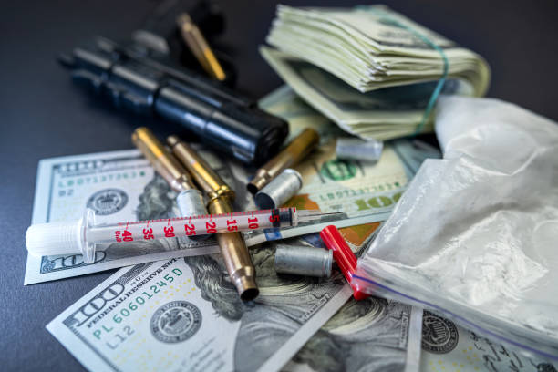 des paquets de drogues en poudre et des billets d’un dollar à côté d’un couteau, d’une arme à feu et d’une seringue médicale. - narcotic gun medicine currency photos et images de collection
