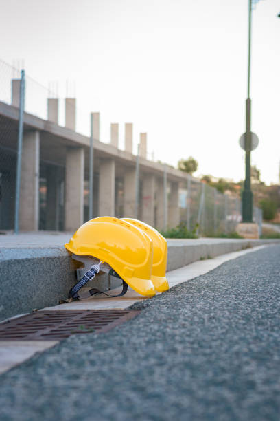 istock Two yellow helmets perched on the sidewalk with a construction site in the background 1461688436