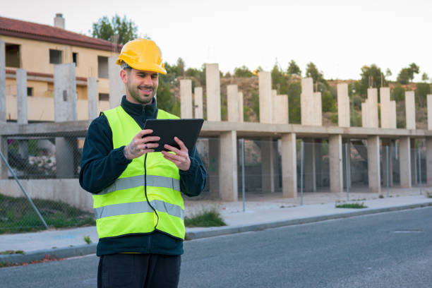 istock Worker looks at a tablet with a building under construction in the background 1461688468