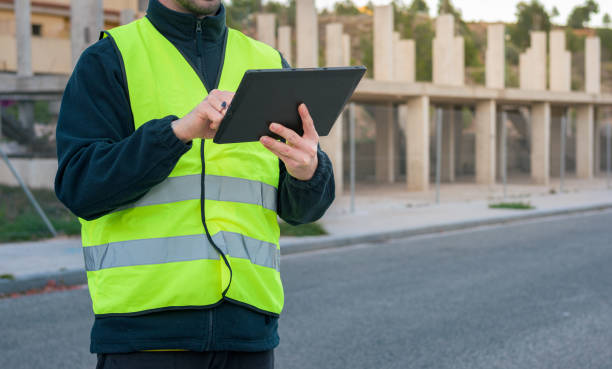 istock Close-up of a worker looking at a tablet with a building under construction in the background 1461688470