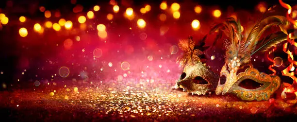 Photo of Carnival Party - Venetian Masks On Red Glitter With Shiny Streamers On Abstract Defocused Bokeh Lights