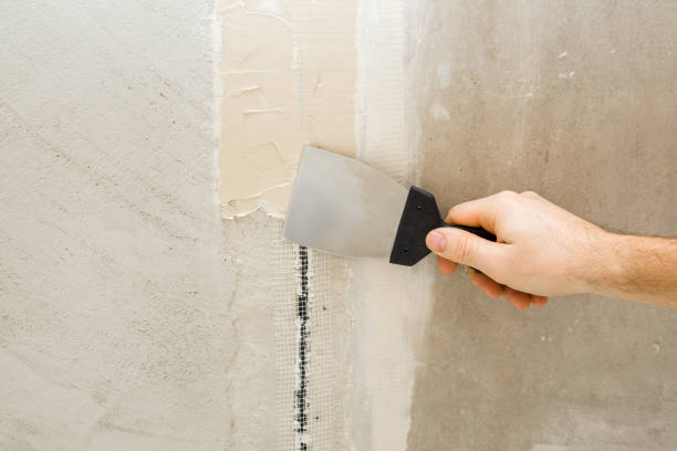 istock Young adult man hand using spatula and plastering concrete ceiling or wall with putty on mesh in electric wire channel. Closeup. Repair work of home. Renovation process. 1461715546