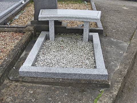 Marble bench next to a grave in a cemetery.