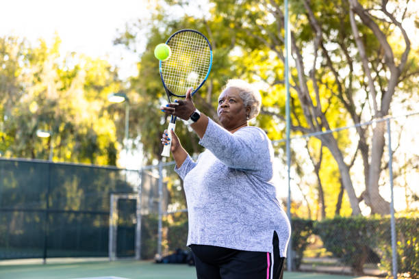 mujer negra mayor jugando tenis - tennis senior adult adult mature adult fotografías e imágenes de stock