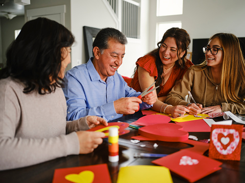 A hispanic family making Valentines Day cards together in a home.