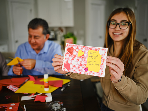 A hispanic family making Valentines Day cards together in a home.