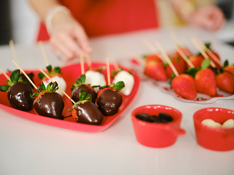 A hispanic family making chocolate dipped strawberries in a home kitchen.