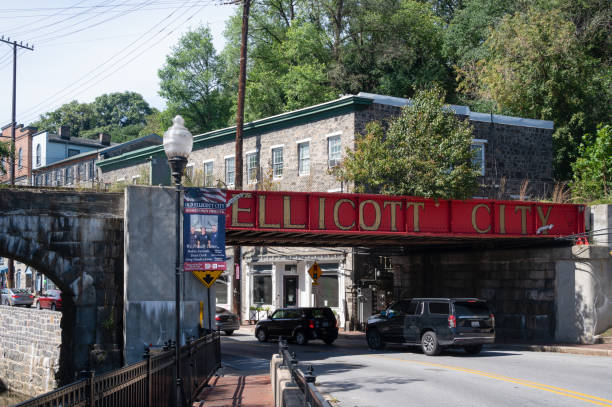 A red painted railroad bridge welcomes visitors to the Ellicott City Historic District Ellicott City, Maryland, USA - September 24, 2021: A red railroad bridge welcomes visitors  to the Ellicott City Historic District. Ellicott City's historic downtown – the Ellicott City Historic District – lies in the valleys of the Tiber and Patapsco rivers. ellicott city maryland stock pictures, royalty-free photos & images