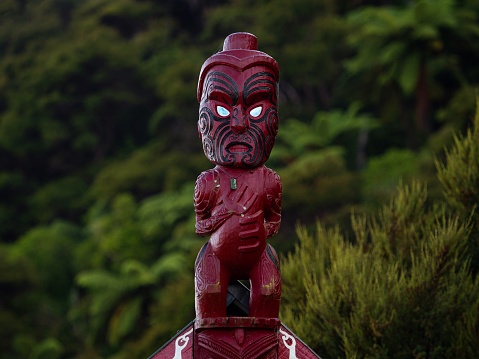 Traditional ancient red wooden Maori sculpture figure in Abel Tasman National Park Nelson Tasman South Island of New Zealand
