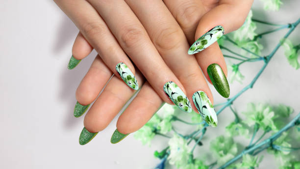 istock Flower nail design. Green manicure on sharp, long nails close-up on a flower background with painted flower design. 1461739325