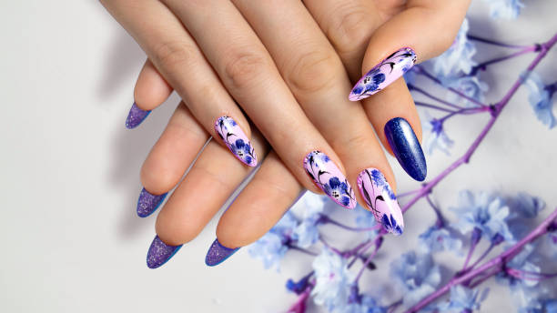 istock Flower nail design. Dark blue manicure on sharp long nails close-up on a flower background with painted flower design. 1461739326