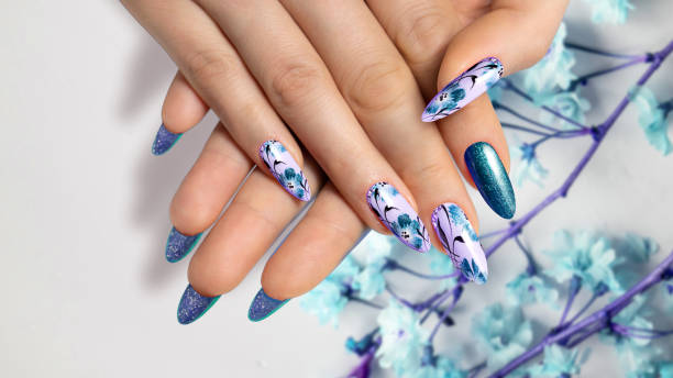istock Flower nail design. Blue color manicure on sharp long nails close-up on a flower background with painted flower design. 1461739327