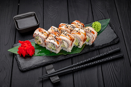 Sushi rolls japanese food on a dark background. Roll with eel. California Sushi roll with tuna, vegetables and unagi sauce closeup. Japan restaurant menu.