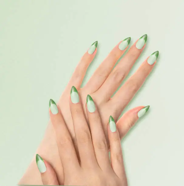Hands With Bright Green Manicure On light Green Background. Close Up Of Female Hands With Trendy Green Nails On Green Background.