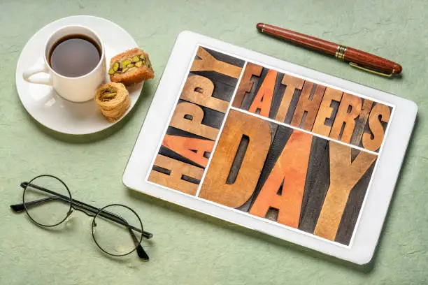 happy father's day - a word abstract in vintage letterpress wood type on a digital tablet with a cup of coffee, greeting card