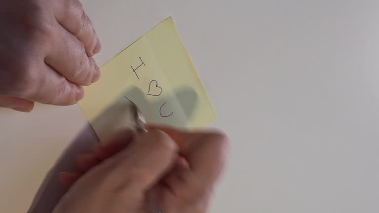 4k video of woman's hands writing: I love you on a post it