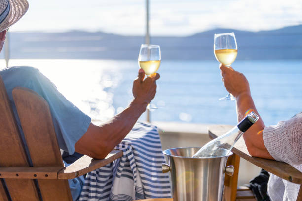 Couple relaxing and drinking wine on deck chairs in an over water bungalow. stock photo