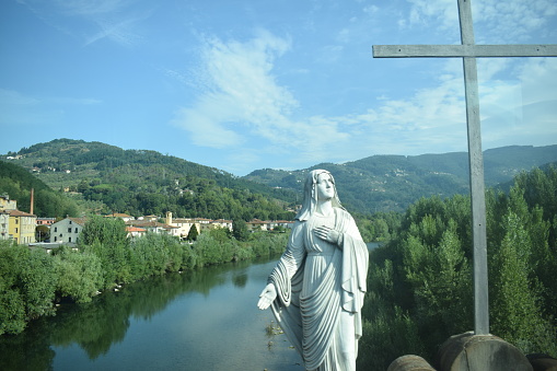 Mary and the cross over the Serchio river in Lucca, Italy.