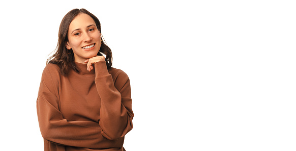 Banner size shot of a young smiling woman holding hand under her chin over white background.