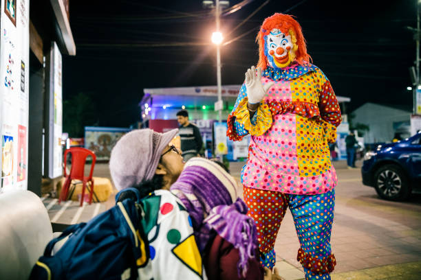 Kolkata, West Bengal, India, 02/02/2023:\nOne clown is interacting with a little boy and with the mother of the boy at the 46th International Kolkata Book fair, at Central Park, Salt Lake City, Kolkata, West Bengal, India, duration 31st December 2022 to 12th February 2023. This is my baby son so no minor model release is required for this image. \n\nThe International Kolkata Book Fair (formerly Calcutta Book Fair) is a winter fair in Kolkata. It is a unique book fair in the sense of not being a trade fair—the book fair is primarily for the general public rather than whole-sale distributors. It is the world's largest non-trade book fair, Asia's largest book fair and the most attended book fair. It is the world's third-largest annual conglomeration of books after the Frankfurt Book Fair and the London Book Fair. Many Kolkatans consider the book fair an inherent part of Kolkata, and instances of people visiting the fair every day during its duration are not uncommon.