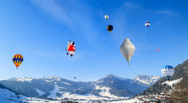 mongolfiere colorate che volano e galleggiano sopra il villaggio delle alpi svizzere chateau d'oex - traditional festival adventure air air vehicle foto e immagini stock