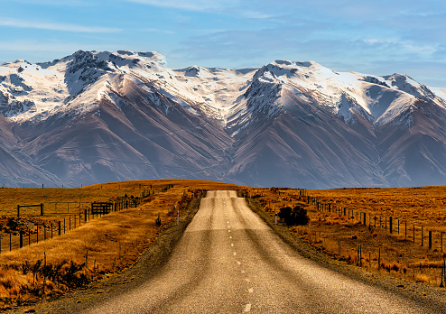 The long straight highway heading to Lake Ohau and the snow covered alps mountain range further on