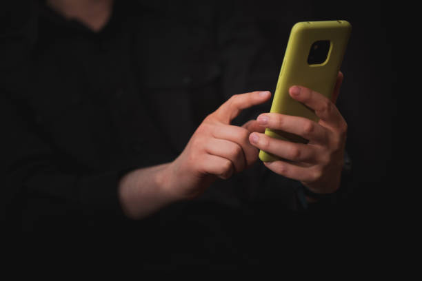 istock man interacting with his mobile phone, black background, communications theme 1461798722