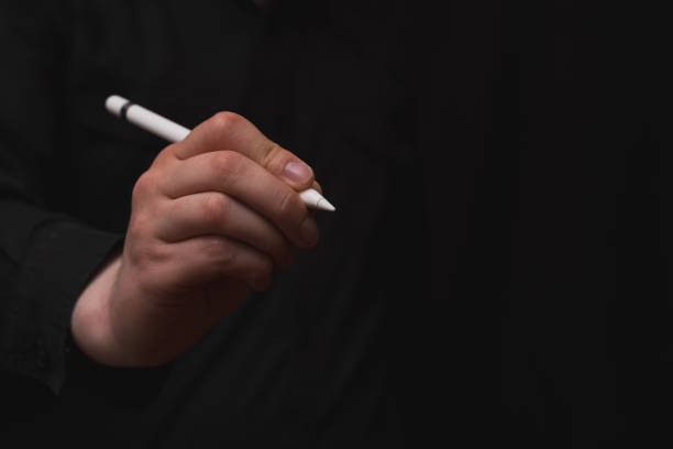 istock digital writing, hand holding digital pen, zero paper use, black background 1461798793