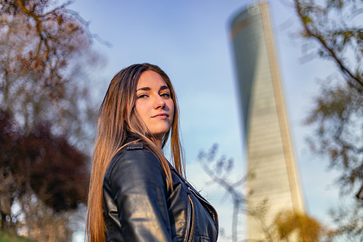 Madrid, Spain. Serene young woman looking at camera against urban background of skyscrapers