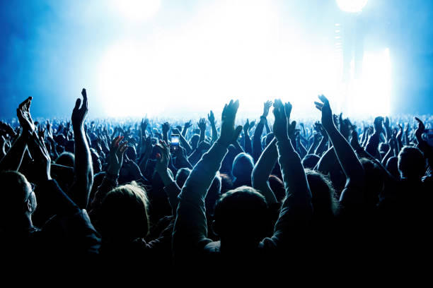 A crowd of people with raised arms during a music concert with an amazing light show. Black silhouettes A crowd of people with raised arms during a music concert with an amazing light show. Black silhouettes. concert hall stock pictures, royalty-free photos & images