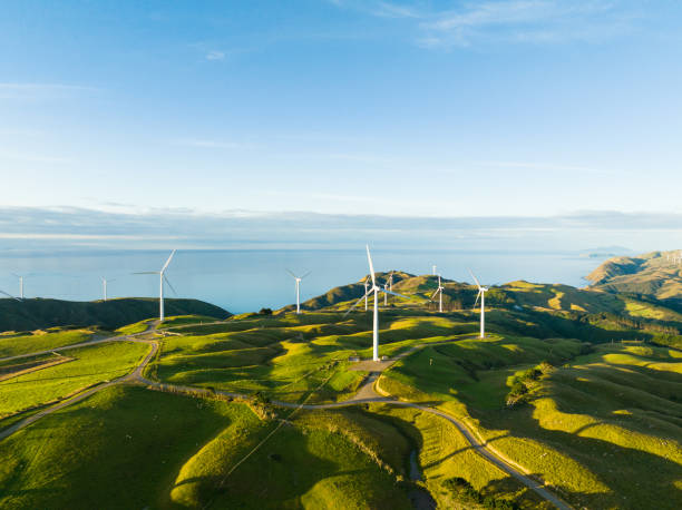 Overhead view of windmills with coast in background. Beautiful scenic view of windmills scattered across the hills with coast in backdrop in New Zealand. renewable energy stock pictures, royalty-free photos & images