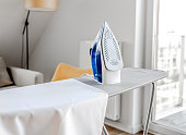 Iron for wrinkled clothes on ironing board in room