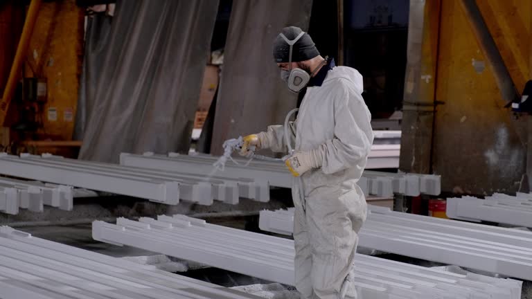 Man painting metal in factory