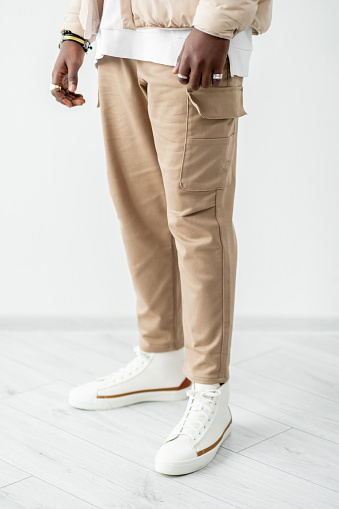 Catalogue fashion studio shoot. Man legs in cargo trousers. Trendy beige outfit.