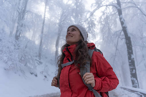Winter adventures. Female tourist on a winter hike in snowcapped mountain forest.