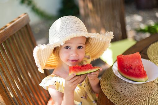 Little girl eating watermelon on summer day outside