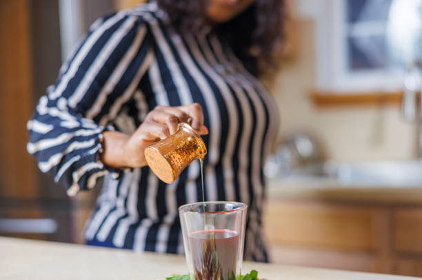 istock A mature attractive Black African-American woman is making herbal tea in her kitchen, adding some honey into a cup. Closeup photo with the selective focus on the foreground. 1461855631