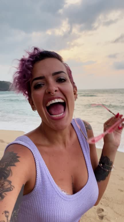 Smiling woman taking selfies on the beach