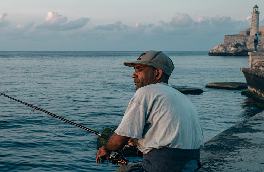 Havana, Cuba - December 10th 2022: The Malecón, Old Havana, Cuba, Fisherman at the entrance of the Havana bay, in front of the Morro Castle. Malecon is one the most popular attractions in Havana both to tourists and locals.