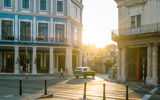 Havana, Cuba - December 12th 2022: Classic vintage cars driving along at old Havana. Old Havana is one the most unique and charming places for tourists in the world for its time-capsuled buildings and lifestyles.