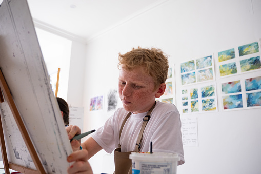 A young boy enjoys painting on an easel in his art class with his friends. Fun art class with my friends