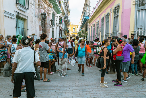 Havana,Cuba, December 9th 2022: Crowd of Cuban People waiting in line for the food in the streets of the Old Havana City during a bright sunny morning.