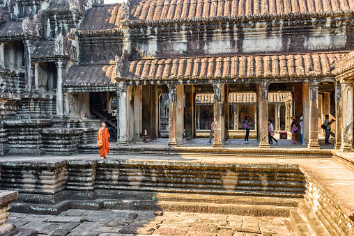 Siem Reap, Cambodia - May 4, 2015: Buddhist monk walking at courtyard of ancient temple complex Angkor Wat. Amazing Angkor Wat is a popular destination of tourists and pilgrims.