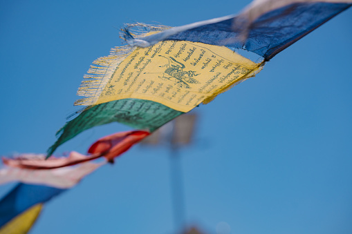 Lungta Prayer flags on blur blue background. A Tibetan prayer flag is a colorful rectangular cloth, often found strung along trails and peaks high in the Himalayas.