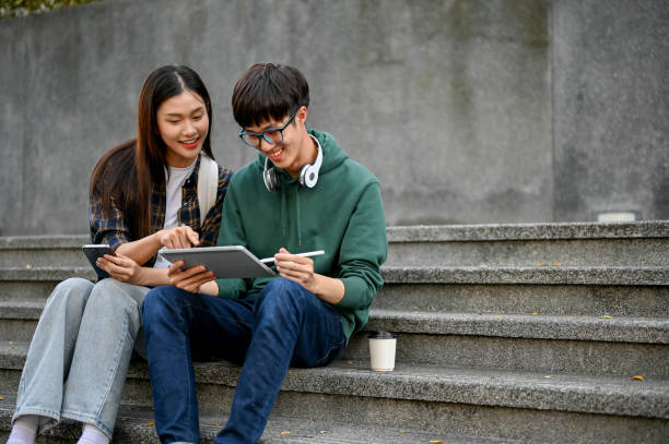 istock Happy Asian college students using tablet on campus building outdoor stairs, discussing their project. 1461922898
