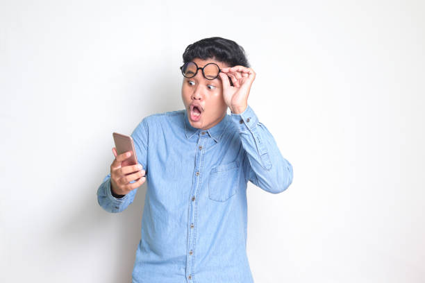 shocked Asian man looking at mobile phone stock photo