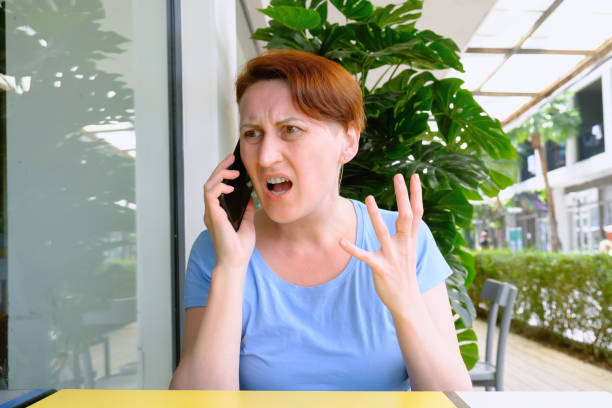 женщина с короткими волосами держит смартфон и яростно кричит в микрофон - furiously стоковые фото и изображения